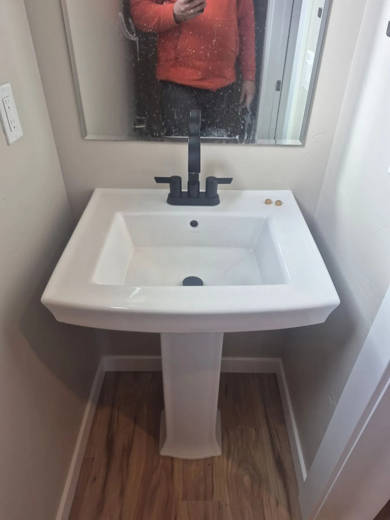 Pedestal sink and black faucet in a finished bathroom