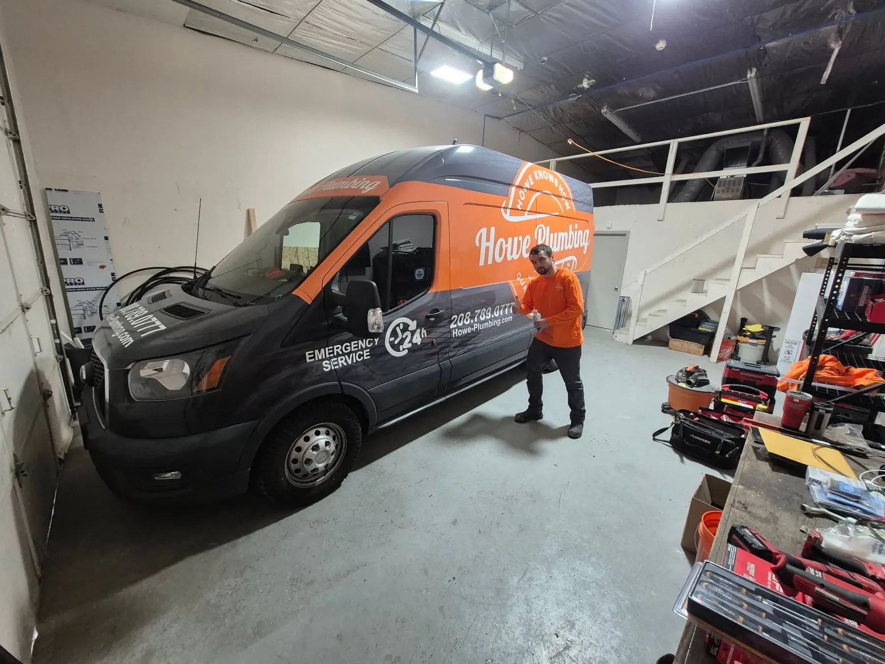 Howe Plumbing technician beside a service van in the shop